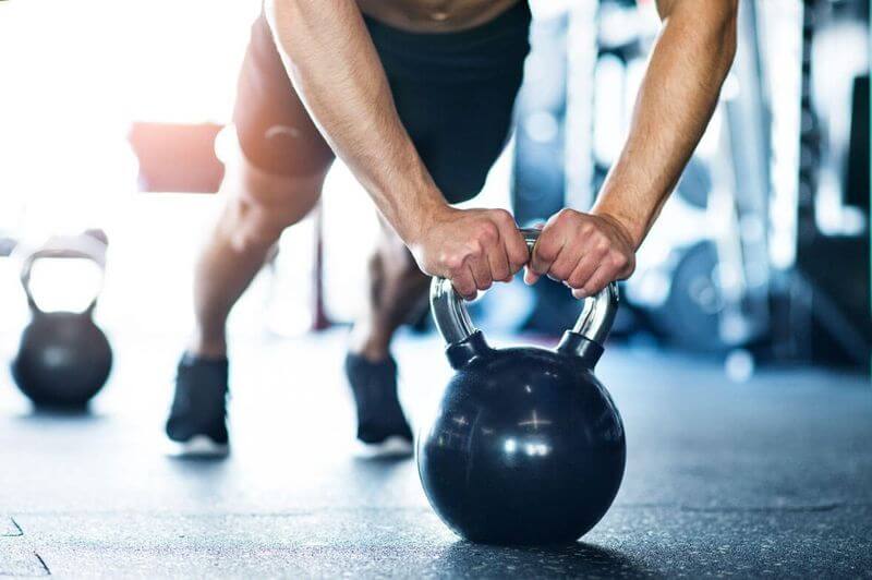 Mann macht Liegestütze auf der Kettlebell