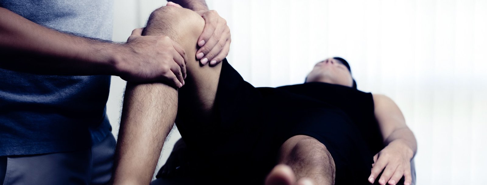 Therapeut mobilisiert das Knie eines Mannes